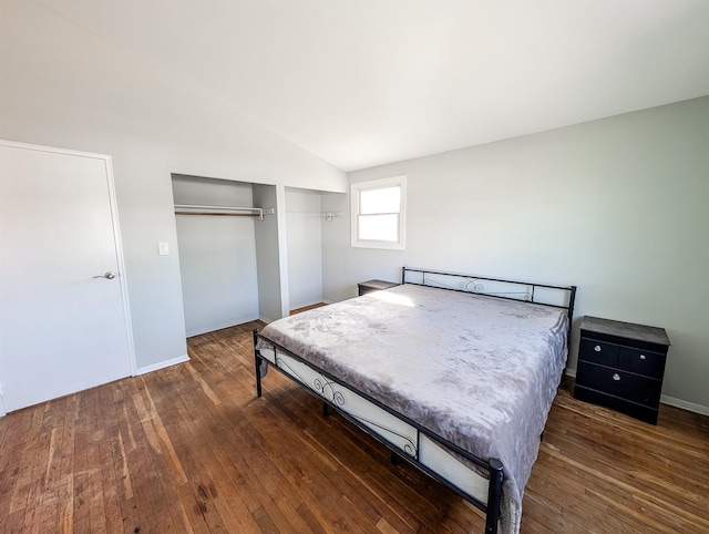 bedroom with a closet, baseboards, vaulted ceiling, and dark wood-style flooring