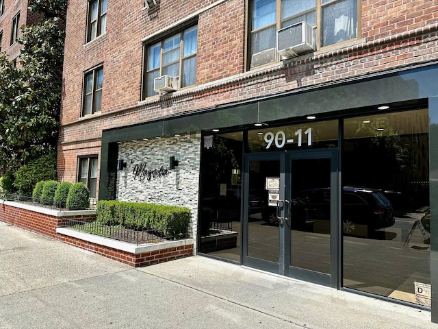 doorway to property featuring brick siding and cooling unit