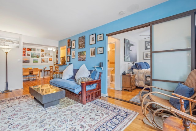 living room with ceiling fan, baseboards, and wood finished floors