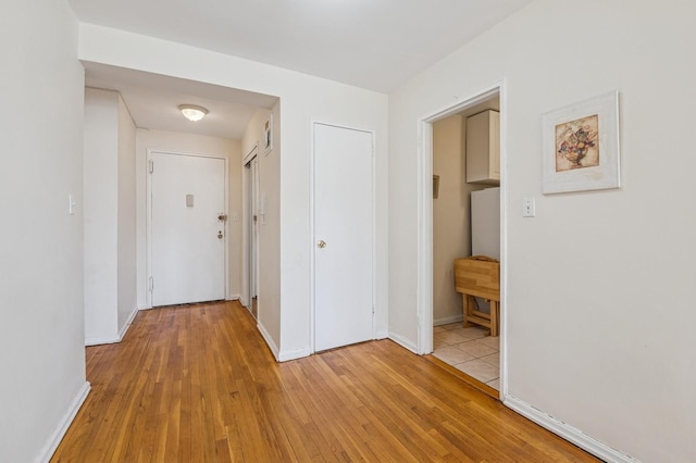 hallway with light wood-style flooring and baseboards