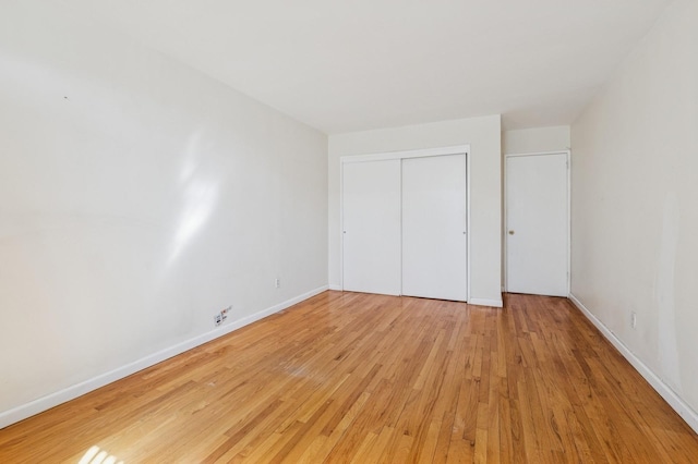 unfurnished bedroom with light wood-type flooring, baseboards, and a closet