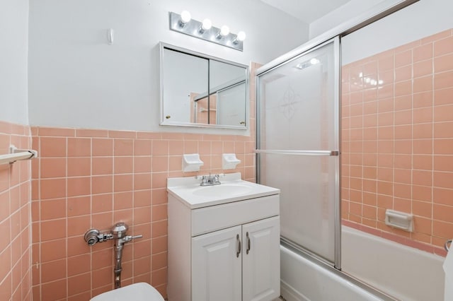 bathroom featuring bath / shower combo with glass door, tile walls, and vanity