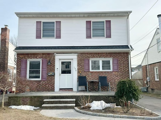 view of front of house with a shingled roof, a porch, and brick siding