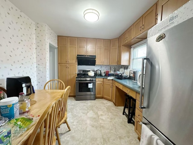 kitchen with stainless steel appliances, dark countertops, brown cabinets, and wallpapered walls