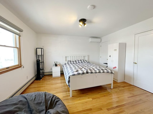 bedroom featuring light wood-style floors, a baseboard radiator, and a wall mounted AC