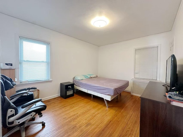 bedroom with light wood-type flooring, radiator heating unit, and baseboards