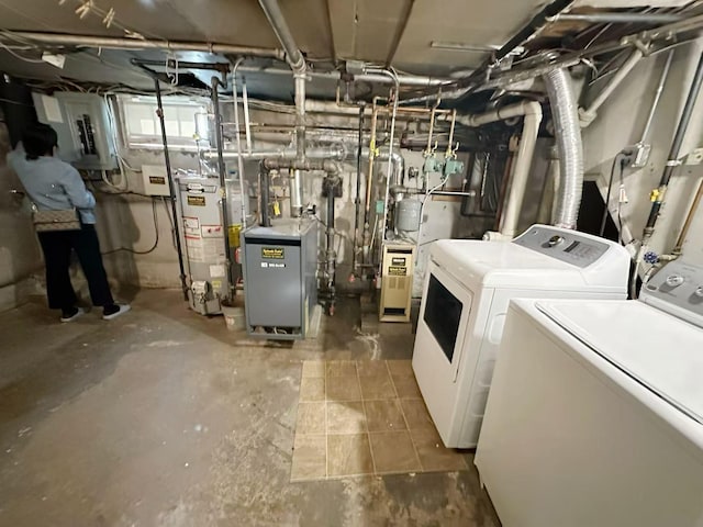 laundry room with laundry area, electric panel, a heating unit, washing machine and clothes dryer, and gas water heater