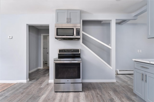 kitchen with a baseboard radiator, gray cabinets, appliances with stainless steel finishes, and light countertops