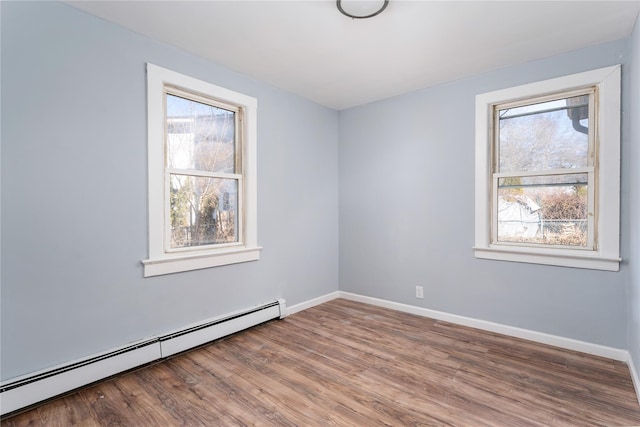 spare room with baseboards, baseboard heating, and wood finished floors