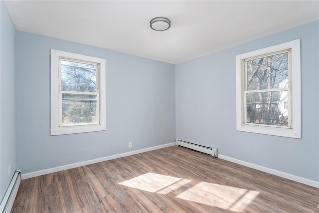 empty room featuring baseboard heating, a baseboard radiator, wood finished floors, and baseboards