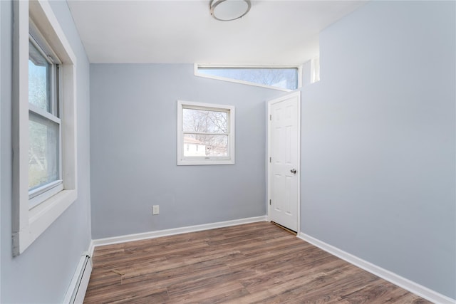 empty room with dark wood-style floors, a baseboard radiator, and baseboards