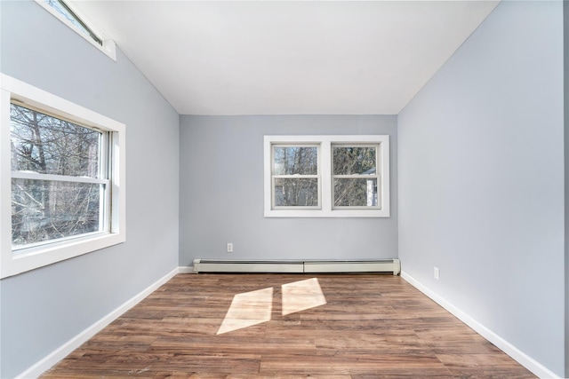 spare room with a baseboard radiator, plenty of natural light, baseboards, and wood finished floors