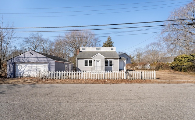 view of front of property featuring a fenced front yard, a detached garage, and an outdoor structure