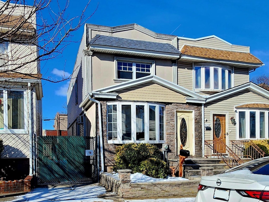 view of front of house with a shingled roof, stone siding, and stucco siding