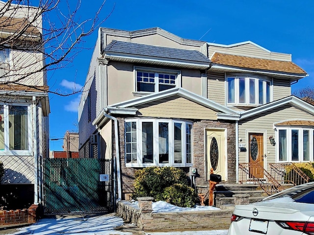 view of front of house with a shingled roof, stone siding, and stucco siding