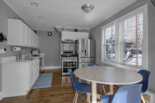 kitchen with a sink, white cabinets, light countertops, appliances with stainless steel finishes, and crown molding