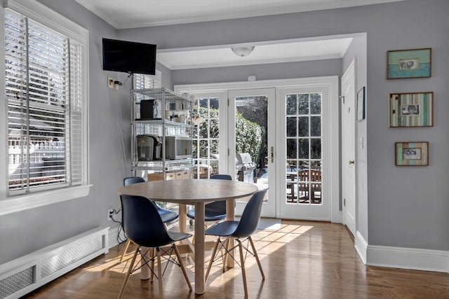 dining area with baseboards, radiator heating unit, ornamental molding, and wood finished floors