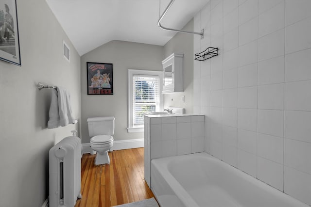 full bathroom with visible vents, toilet, radiator heating unit, vaulted ceiling, and a sink