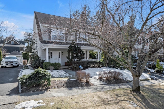 view of front of property with aphalt driveway, covered porch, and a chimney