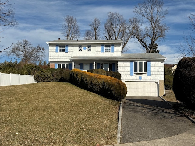 traditional home featuring a garage, fence, driveway, and a front lawn