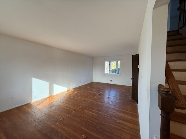 unfurnished living room with dark wood finished floors and stairway