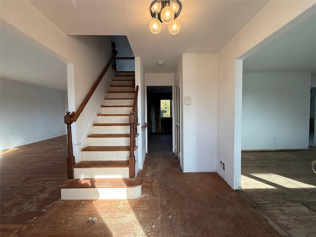 staircase with visible vents and a chandelier