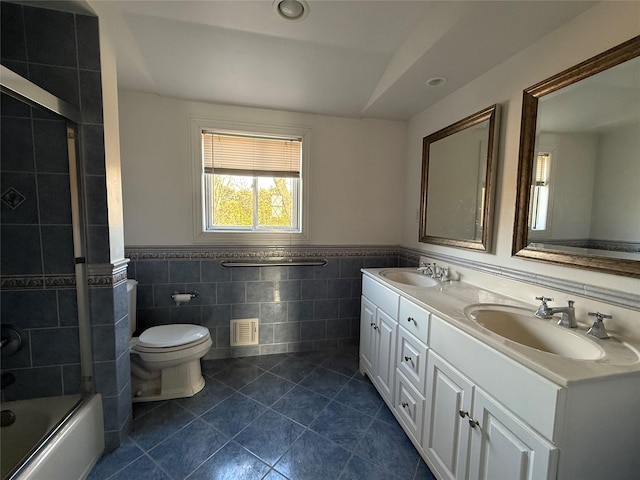 bathroom featuring toilet, visible vents, a sink, and combined bath / shower with glass door