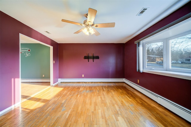 unfurnished room featuring a baseboard heating unit, baseboards, visible vents, and light wood-style flooring