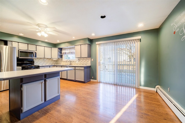 kitchen with a center island, light wood finished floors, appliances with stainless steel finishes, and a baseboard radiator