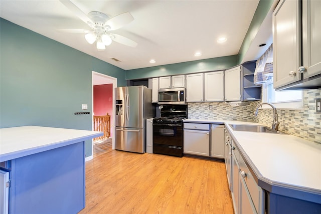 kitchen featuring a sink, light countertops, appliances with stainless steel finishes, tasteful backsplash, and light wood-type flooring