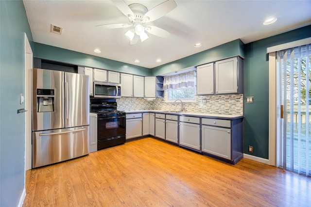 kitchen with light wood finished floors, visible vents, decorative backsplash, stainless steel appliances, and a sink