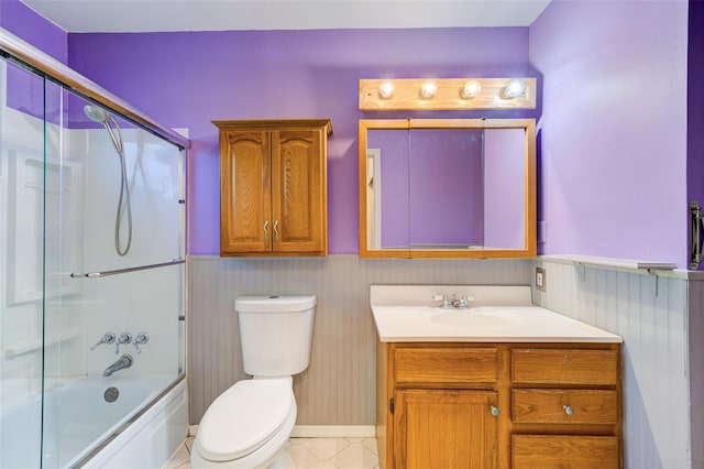 full bath featuring vanity, toilet, a wainscoted wall, and enclosed tub / shower combo