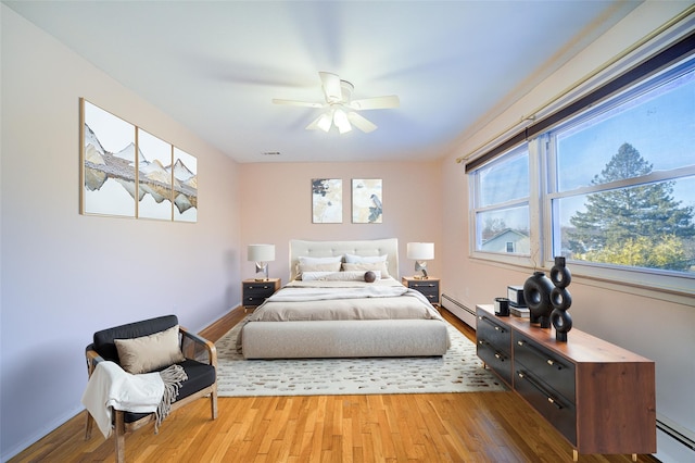 bedroom featuring a baseboard heating unit, ceiling fan, and wood finished floors