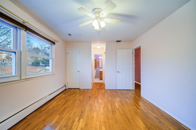 unfurnished bedroom featuring visible vents, ensuite bathroom, a baseboard heating unit, light wood finished floors, and baseboards