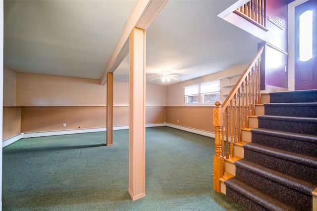 below grade area featuring a ceiling fan, a baseboard heating unit, carpet, baseboards, and stairs