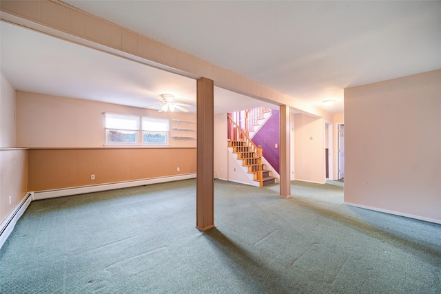 below grade area with stairway, carpet flooring, a ceiling fan, and baseboard heating