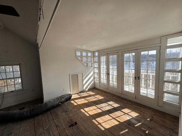 unfurnished living room featuring lofted ceiling, a wealth of natural light, wood finished floors, and french doors