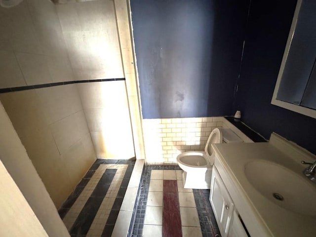 bathroom with toilet, tile patterned flooring, tile walls, and vanity