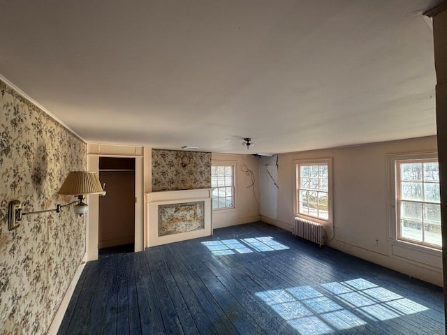 unfurnished living room with wallpapered walls, radiator heating unit, baseboards, and dark wood finished floors