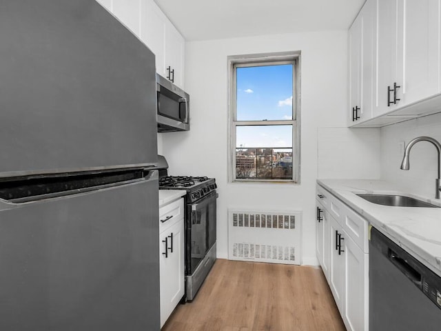 kitchen featuring light stone counters, white cabinets, a sink, and black appliances