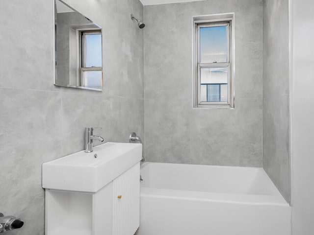 full bath featuring shower / bathtub combination, vanity, and tile walls