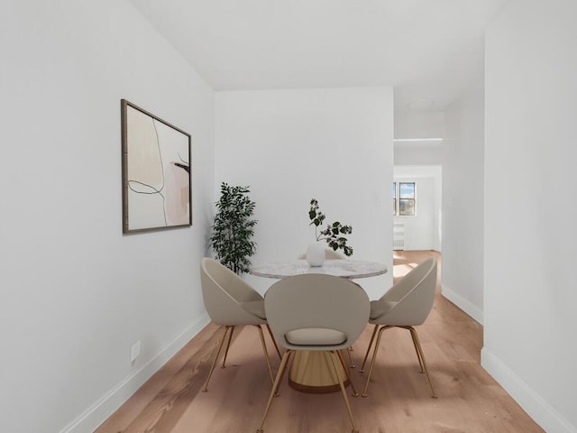 dining space featuring light wood-type flooring and baseboards