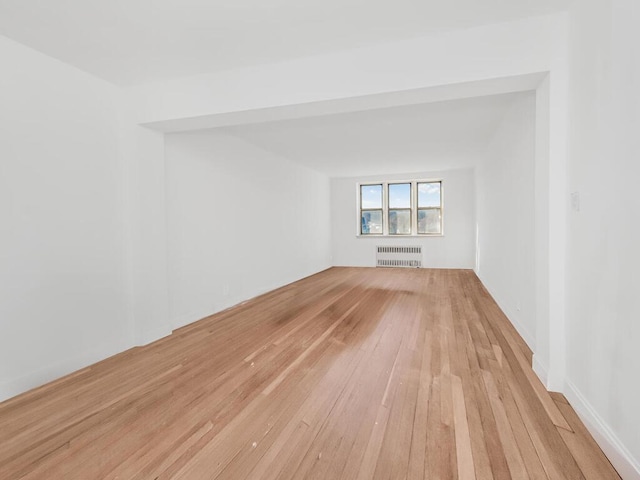 unfurnished room featuring light wood-style flooring and radiator