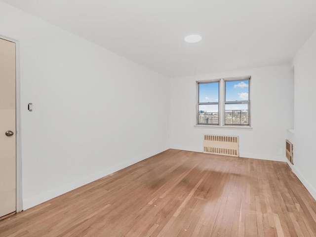 spare room with light wood-type flooring and radiator heating unit