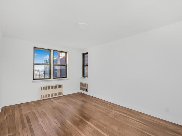 unfurnished room featuring radiator, heating unit, and wood finished floors