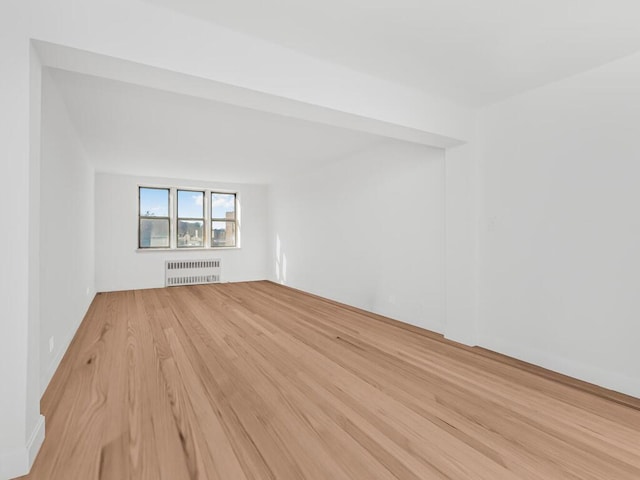 unfurnished room featuring wood finished floors and radiator