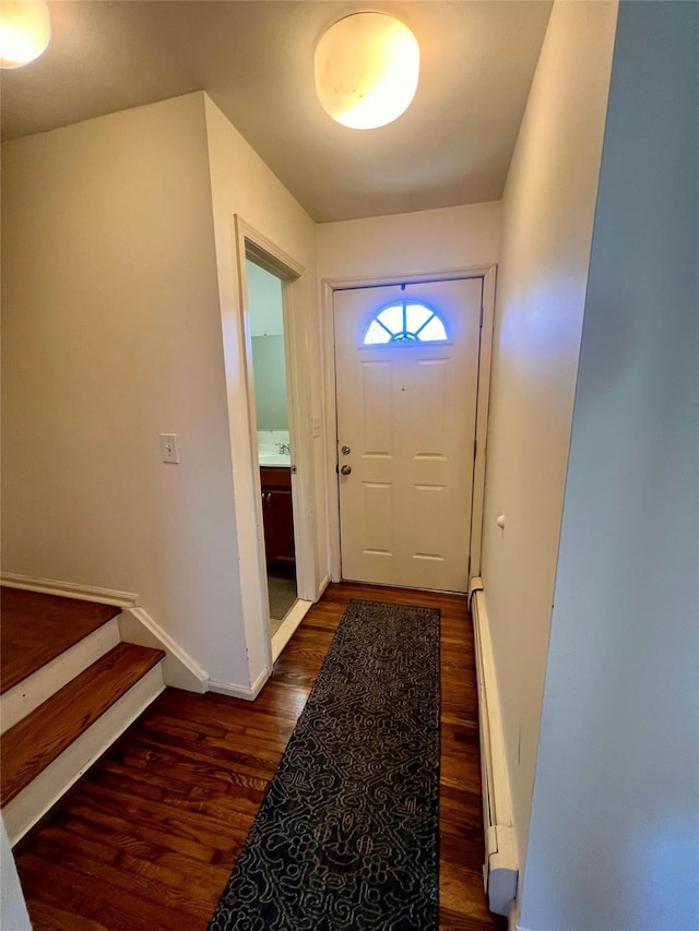 entryway with a baseboard heating unit, dark wood-type flooring, stairway, and baseboards