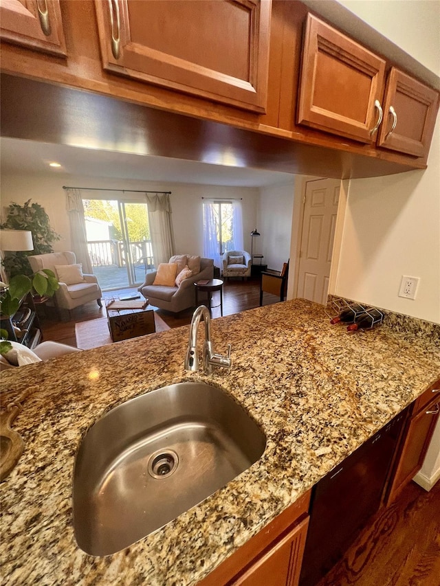 kitchen with light stone countertops, brown cabinetry, and a sink