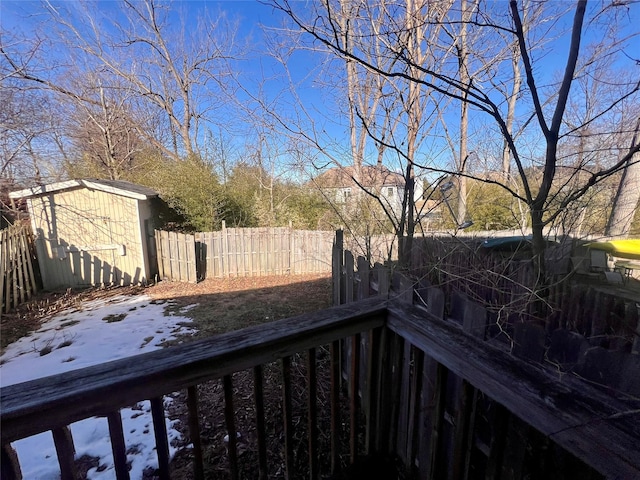 wooden deck with an outbuilding, fence, and a storage unit