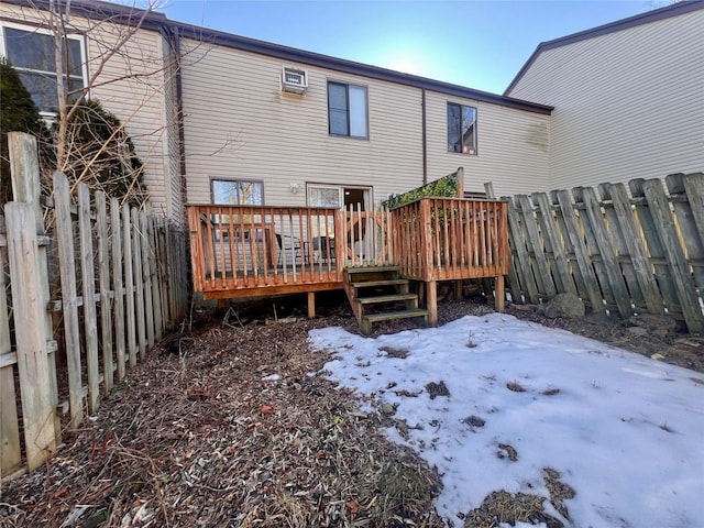 snow covered property with a fenced backyard, a deck, and a wall mounted AC